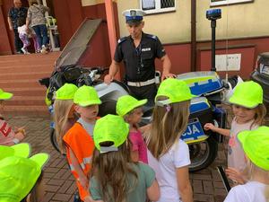 Policjant przy motocyklu pozuje do zdjęcia z dziećmi