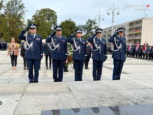 Delegacja policjantów idzie z wiązanka kwiatów