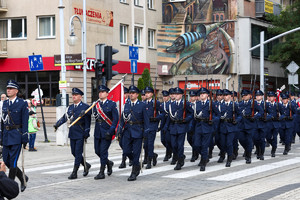 Policjanci ze sztandarami maszerują ulicami miasta