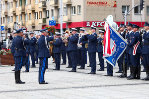 Policjant w asyście innego policjanta oddaje honor pocztom sztandarowym