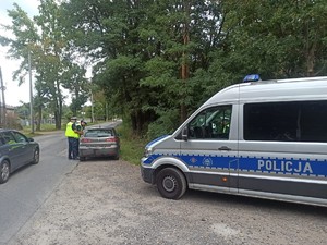 Policjanci rozmawiają z kierującym na drodze, obok stoi policyjny radiowóz