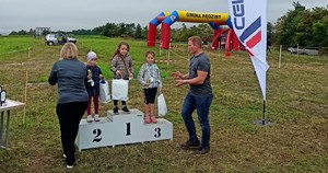 Troje dzieci stoi na podium i chwali się zdobytymi nagrodami