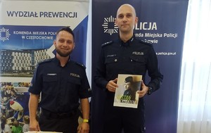 Policjanci przy stoisku służbowym pozują do zdjęcia