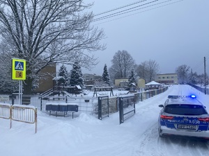 zimowy widok radiowozu na tle szkoły