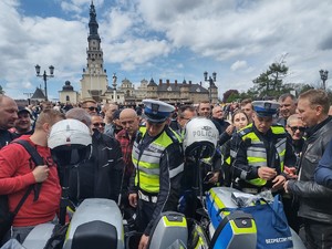 Policjanci na jasnogórskich błoniach wręczają uczestnikom kamizelki odblaskowe