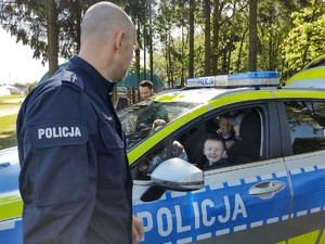 Dziecko za kierownica radiowozu- obok stoi policjant