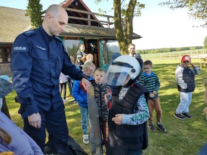 Policjant pomaga ubrać chłopca w policyjny sprzęt
