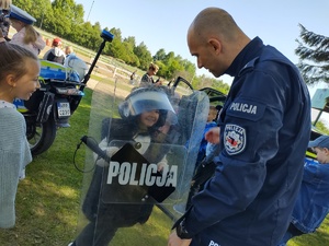 Policjant rozmawia z dzieckiem, które przymierza policyjny sprzęt