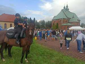 Policjanci na koniach stoją na placu kościelnym wśród dzieci