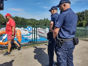 Policjanci sprawdzają oznaczenia przy ogrodzeniu zbiornika wodnego