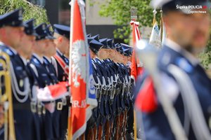 Policjanci ze sztandarami stoją na baczność