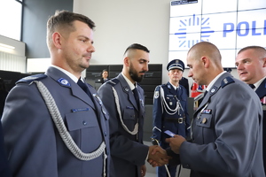 Policjanci stoją w szeregu, a komendant jednemu z nich podaje rękę