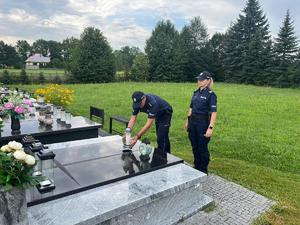 Policjant i policjantka składają znicz na grobie