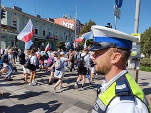 Policjant czuwa nad bezpieczeństwem osób przechodzących przez drogę