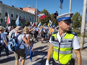 Tłum ludzi maszeruje, a nad ich bezpieczeństwem czuwa policjant