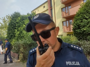 Policjant rozmawia przez stację nasobną