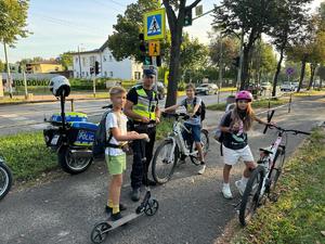 Policjant z dziećmi przy przejściu dla pieszych pozuje do zdjęcia