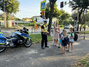 Policjant przy przejściu dla pieszych wręcza element odblaskowy dziecku