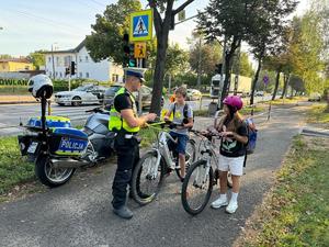 Policjant rozmawia z dziećmi przy przejściu dla pieszych