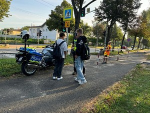 Policjant rozmawia z chłopcami przy motocyklu w rejonie przejścia dla pieszych