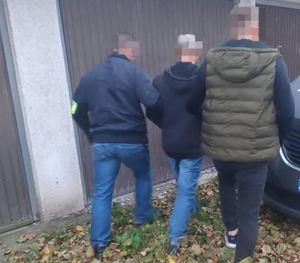 Nieumundurowani policjanci doprowadzają zatrzymanego