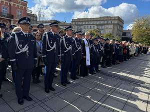 Policjanci w umundurowaniu wyjściowym stoją w szeregu na placu