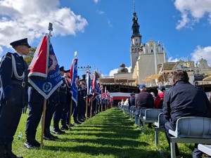 Policjanci ze sztandarami stoją w szeregu pod wieżą Jasnej Góry