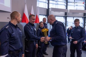 Policjant oficjalnie wśród innych mundurowych odbiera gratulacje i puchar z rak Zastępcy Komendanta Wojewódzkiego Policji w Katowicach