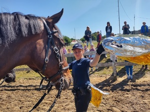 Policjantka stoi przy łbie konia i unosi chustę nad głową