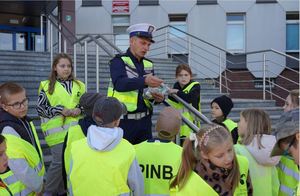 Policjant wręcza dzieciom książeczki