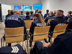 Policjanci siedzą w ławkach i słuchają wykładowcy