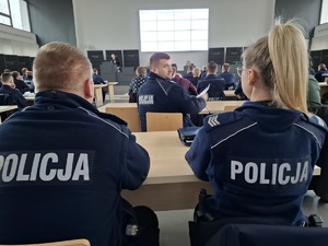 Policjanci siedzą w auli w ławkach i słuchają wykładu