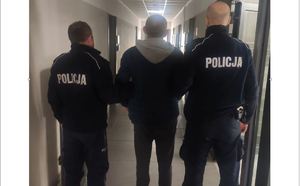 Policjanci doprowadzają zatrzymanego do pomieszczenia służbowego