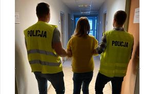 Policjanci doprowadzają zatrzymaną do pomieszczenia służbowego