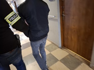 Policjant nieumundurowany doprowadza zatrzymanego do pomieszczenia służbowego