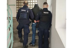 Policjanci doprowadzają zatrzymanego po schodach