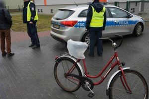 Policjanci rozmawiają z mężczyzna przy radiowozie, obok stoi rower