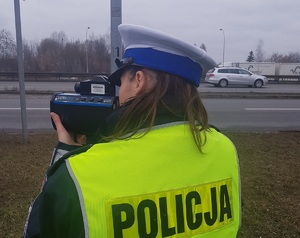 Policjantka trzyma miernik prędkości i mierzy na drodze