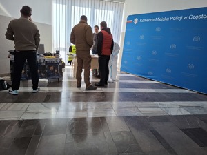 Kandydaci stoją przy policyjnym stoisku i rozmawiają z kobietą