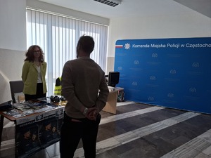 Mężczyzna stoi przy policyjnym stoisku i rozmawia z kobietą