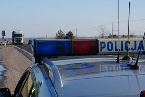 Napis Policja na dachu radiowozu, w tle ruch uliczny