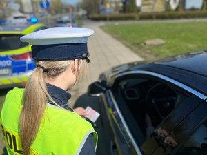 Policjantka kontroluje pojazd, w ręce trzyma dokument