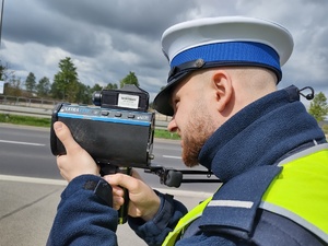 Policjant trzyma przy twarzy urządzenie, w które patrzy