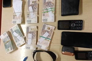 Zabezpieczona gotówka, telefony i pasek leżą ułożone na stoliku