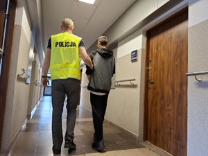 Policjant doprowadza zatrzymanego