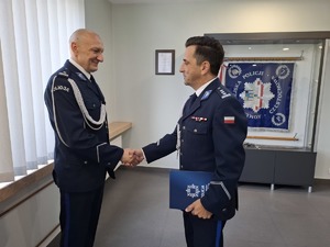Komendant gratuluje policjantowi i podają sobie prawe dłonie