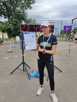 Policjantka w stroju sportowym pozuje do zdjęcia z dyplomem