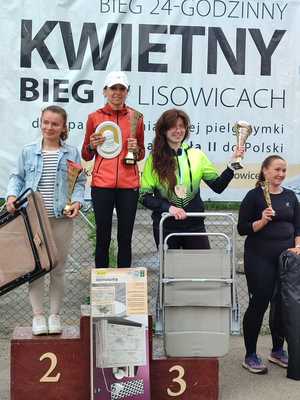 3 kobiety w strojach sportowych stoją na podium