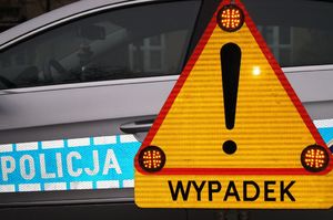 pojazd policyjny i żółty znak w kształcie trójkąta  z napisem wypadek
