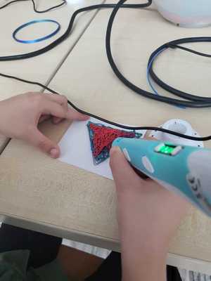 Ręka dziecka wykonuje pracę plastyczną
